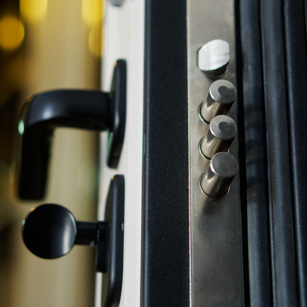 Gros plan sur une porte sécurisée avec poignée noire et plusieurs verrous argentés.