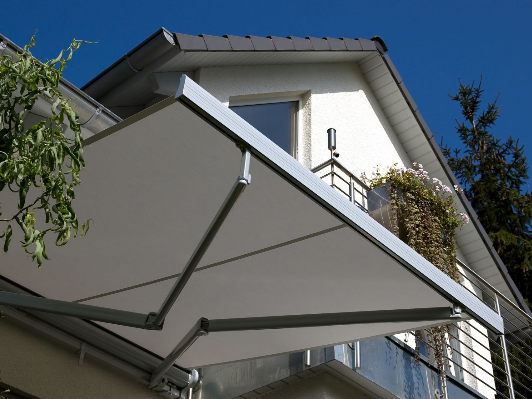 Un store blanc surplombe le balcon d'une maison blanche.