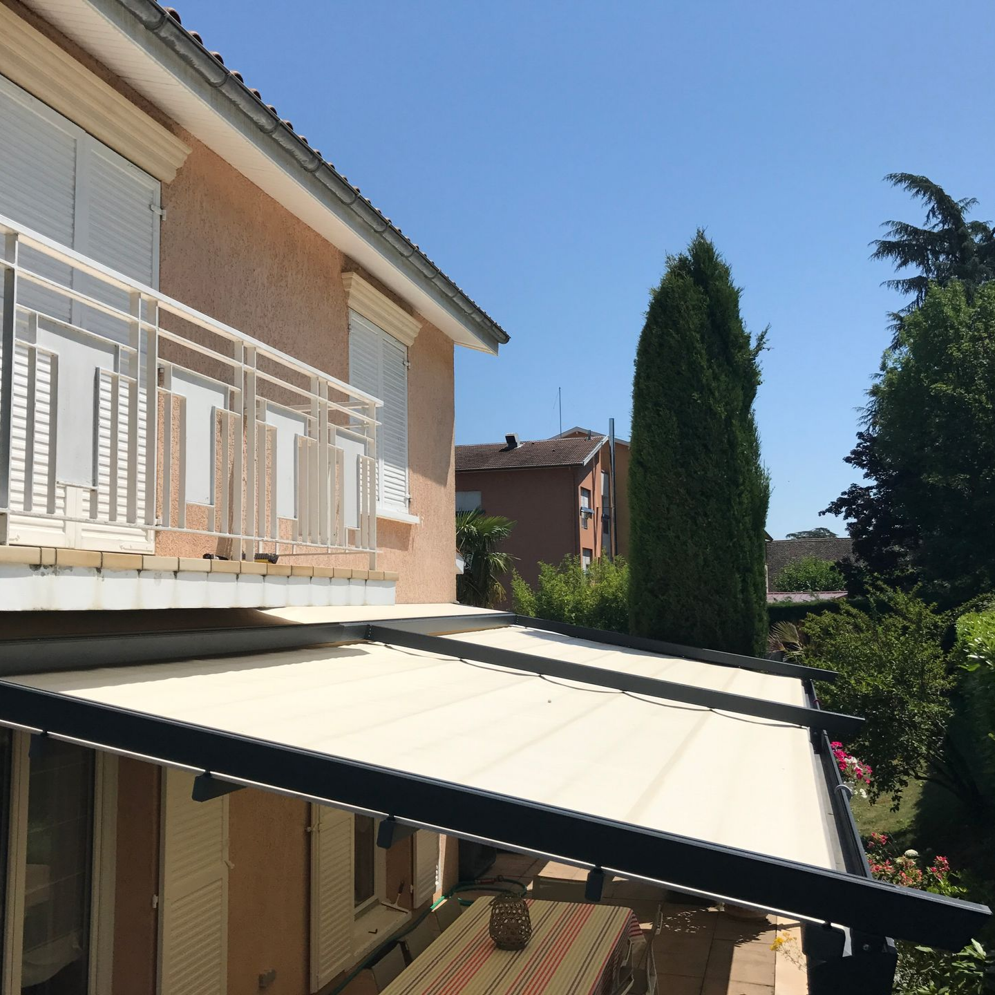 Auvent beige au-dessus d'une terrasse.