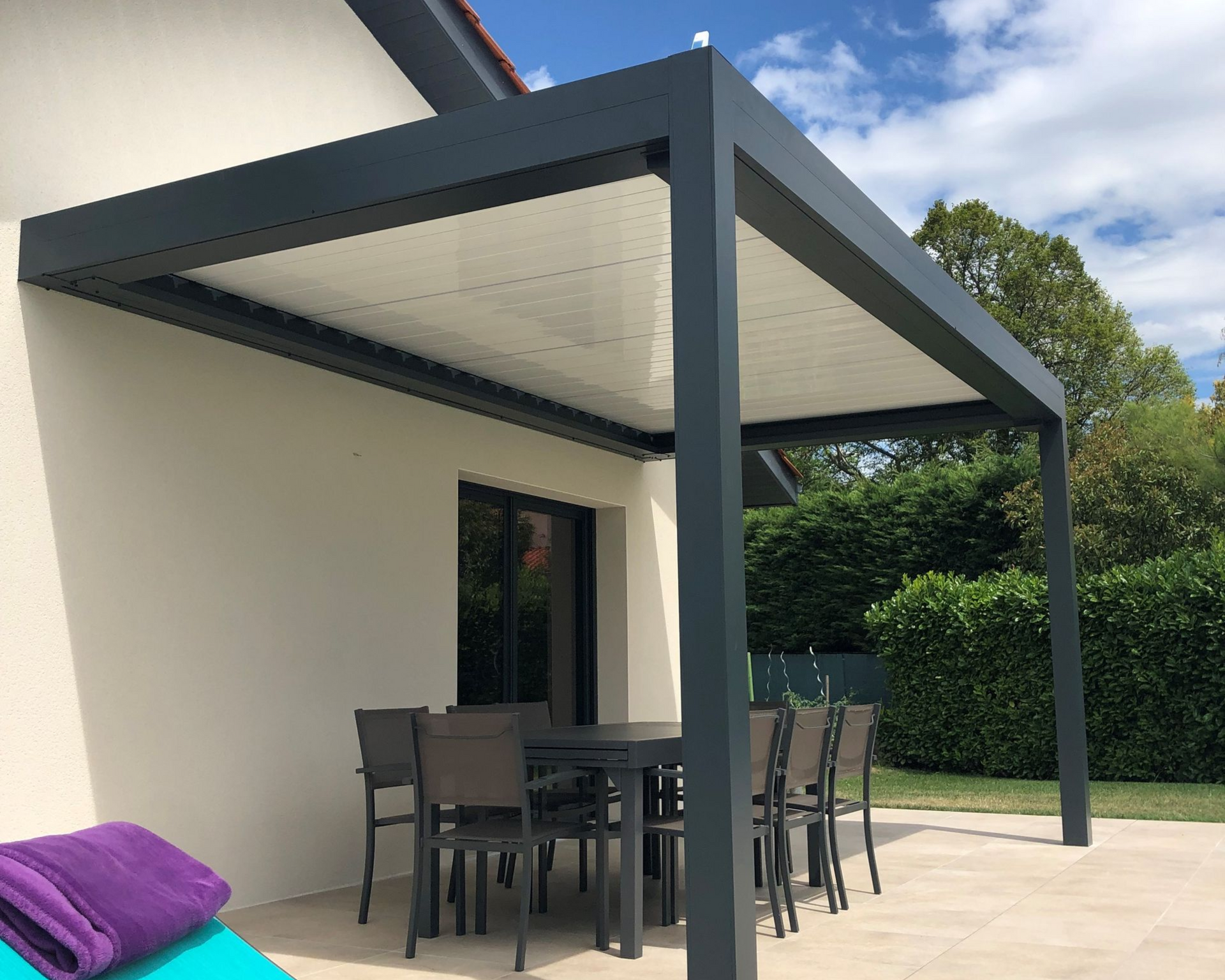 Terrasse avec coin repas couvert et table dressée. Pergola rétractable.