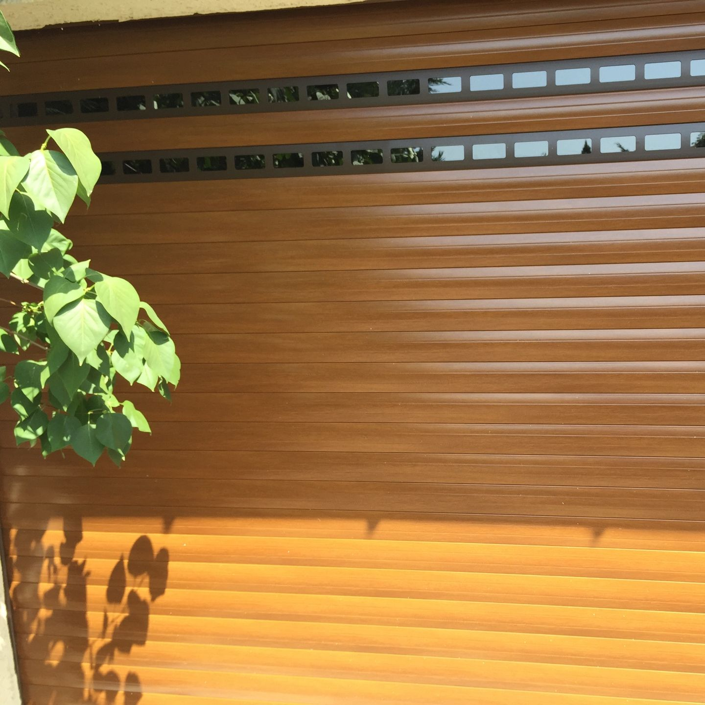 Porte de garage enroulable marron avec fentes d'aération.