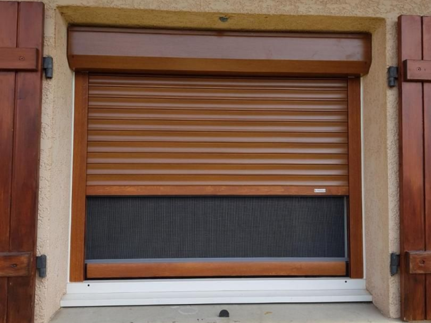 Volet marron fermé sur une fenêtre à moustiquaire rétractable.