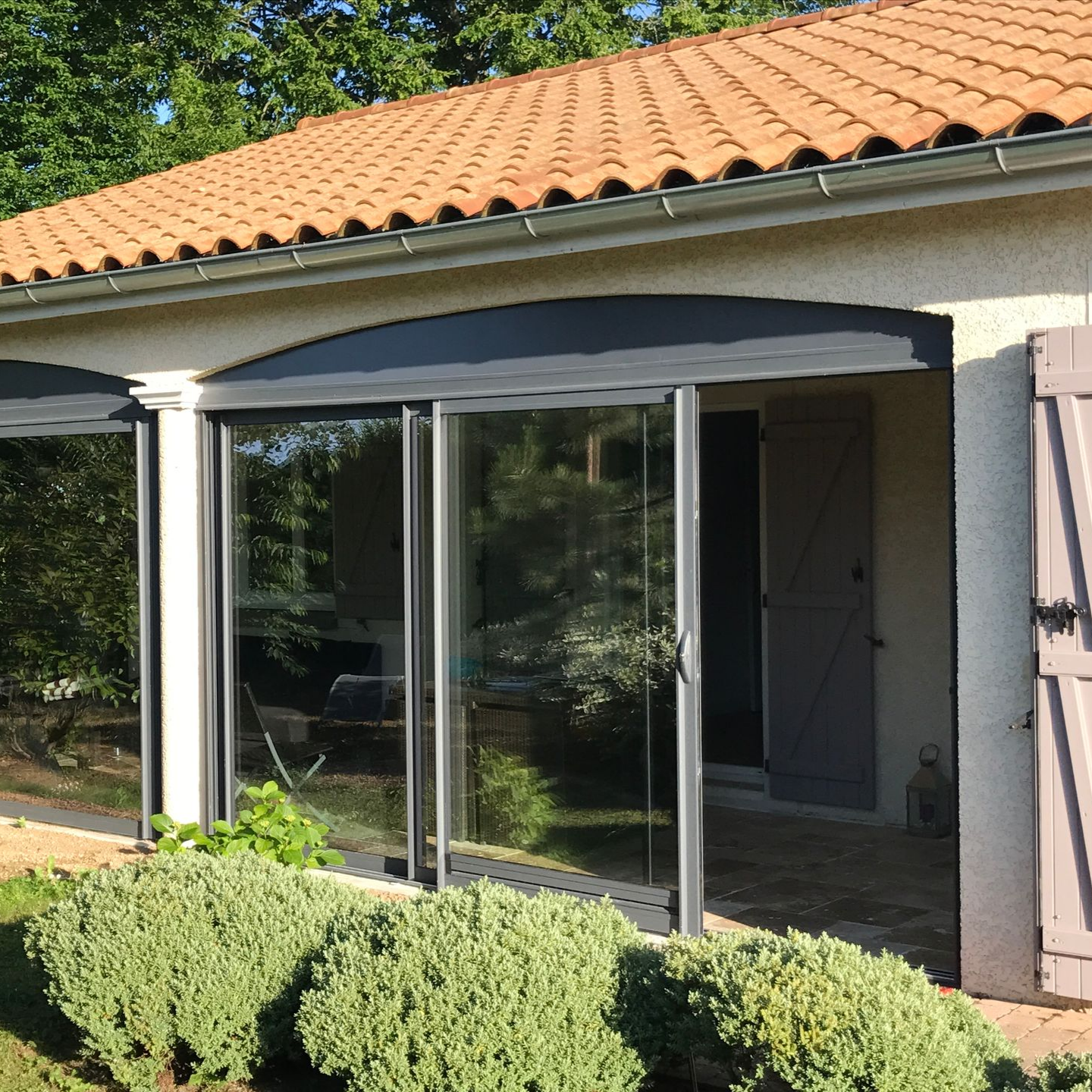 Portes coulissantes en verre avec auvents sous un toit de tuiles.
