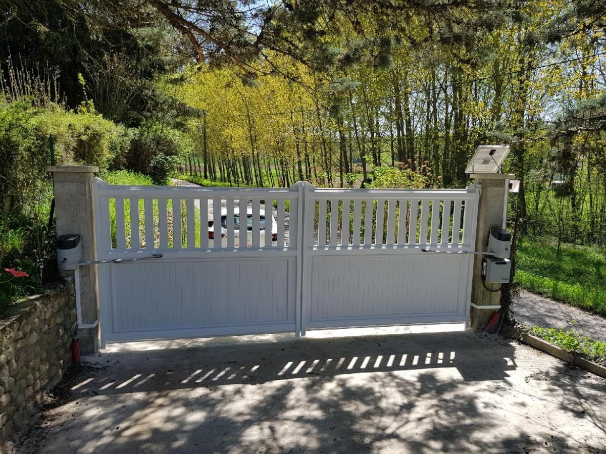 Portail d'allée automatisé blanc devant une maison.