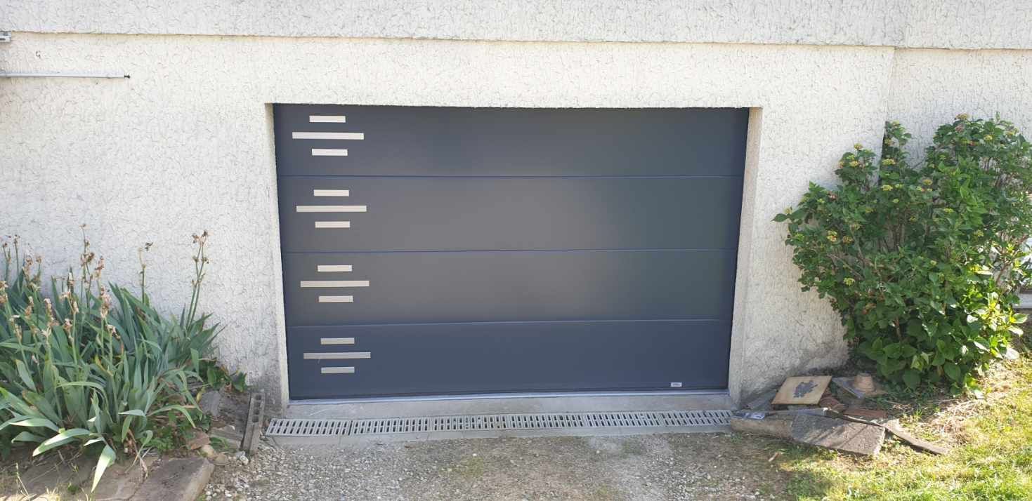 Porte de garage grise à rayures horizontales et barres décoratives argentées.