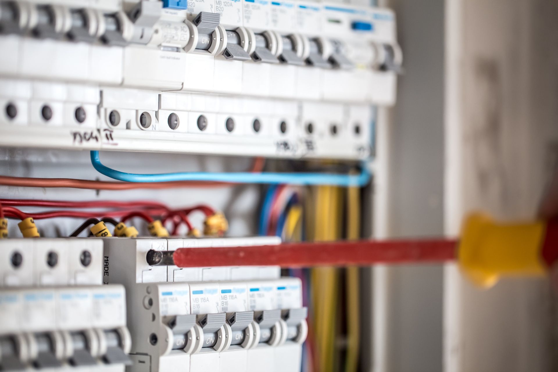 Primer plano de un panel eléctrico con un destornillador que se utiliza para apretar un tornillo.