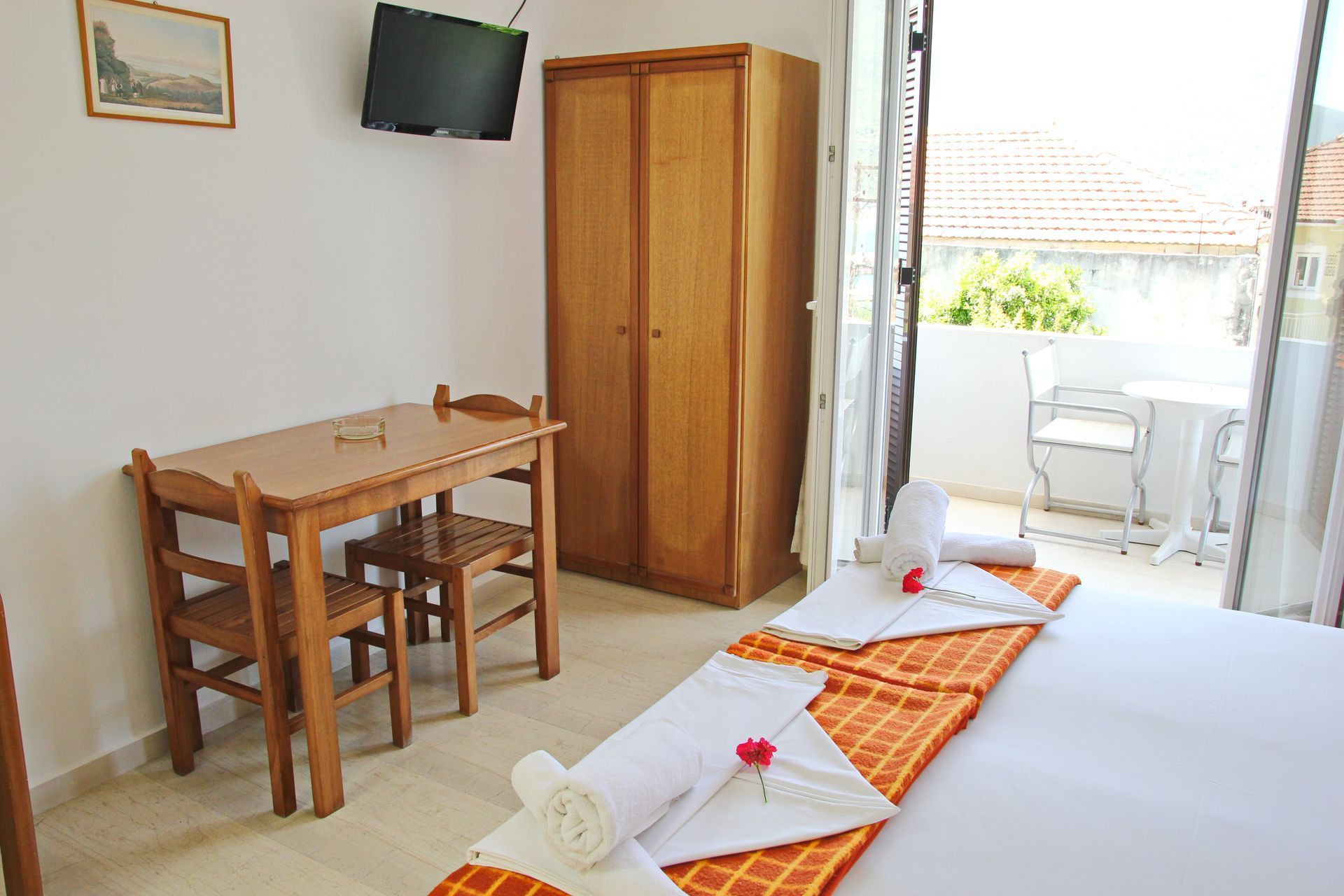 Ένα δωμάτιο ξενοδοχείου με δύο κρεβάτια, μικρό τραπέζι και καρέκλες, ντουλάπα, τηλεόραση και πρόσβαση σε μπαλκόνι.