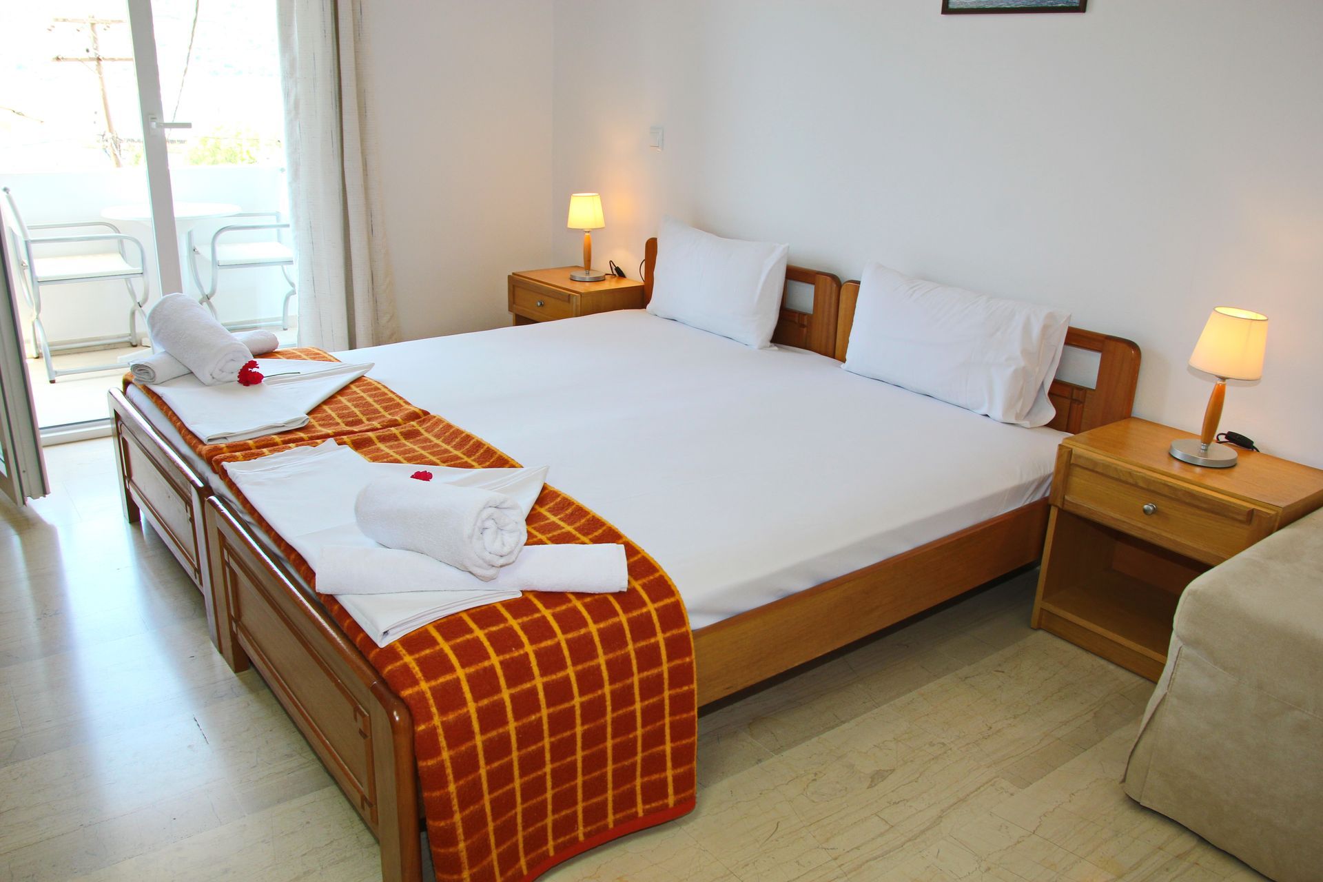 Υπνοδωμάτιο με μεγάλο κρεβάτι, κομοδίνα, μπαλκόνι και πετσέτες στο κρεβάτι.