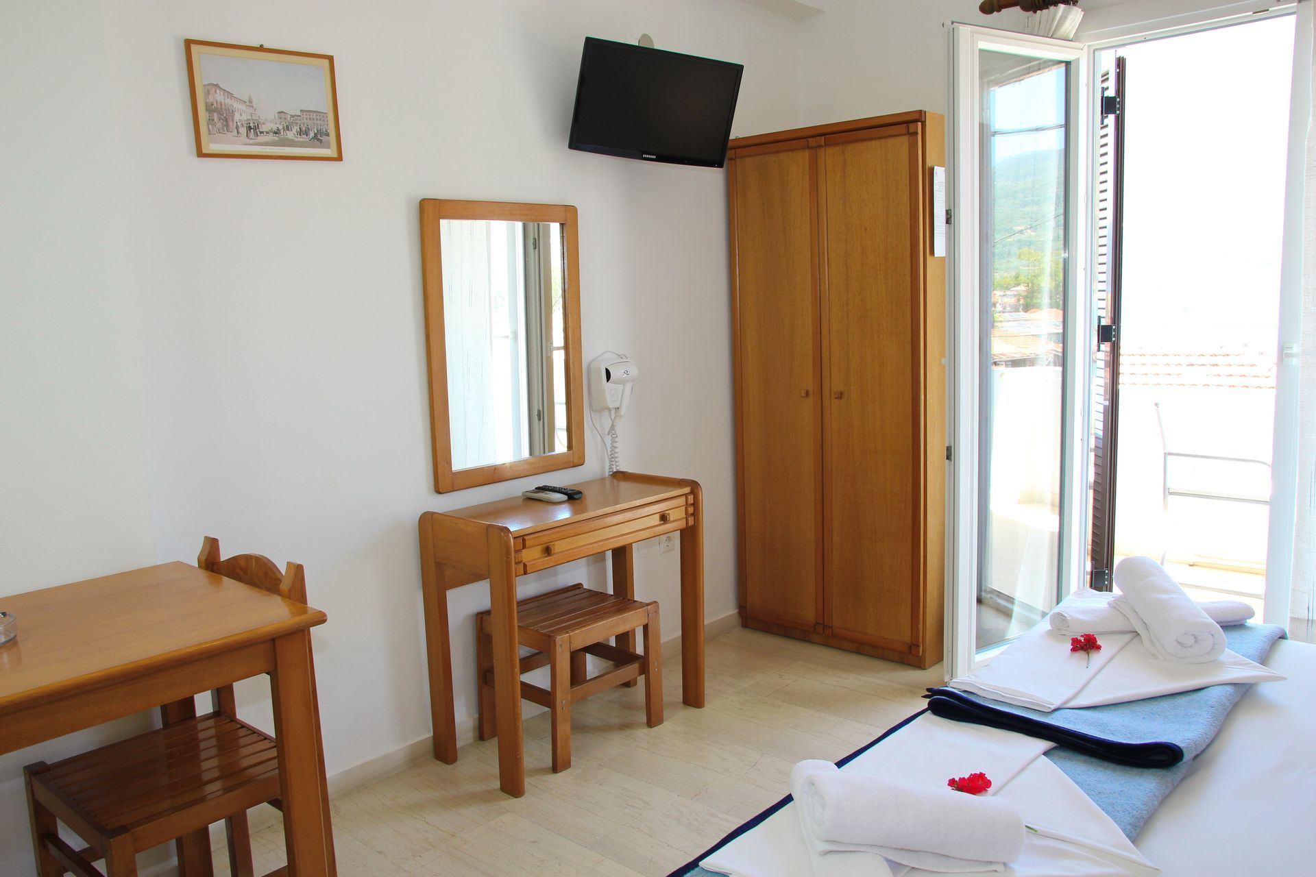 Υπνοδωμάτιο με ξύλινα έπιπλα, μπαλκόνι και κρεβάτι με πετσέτες.