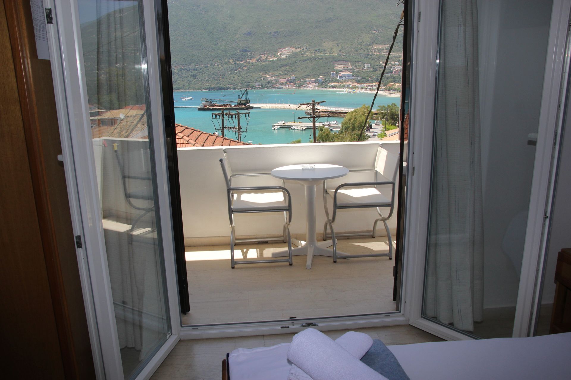 Μπαλκόνι με θέα στο λιμάνι, τραπέζι, καρέκλες και θέα στη θάλασσα.