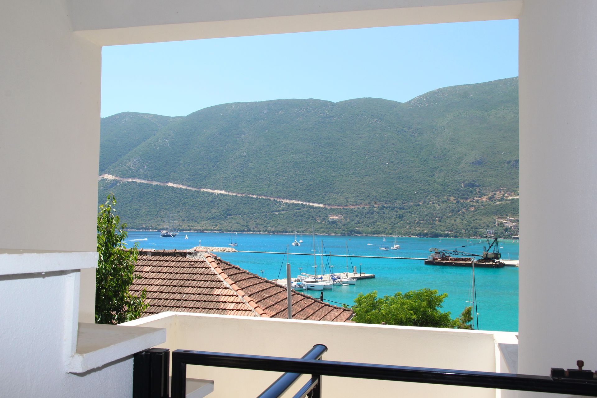 Θέα μέσα από ένα λευκό πλαίσιο ενός τιρκουάζ κόλπου με βάρκες και ένα βουνό σε μια ηλιόλουστη ημέρα.