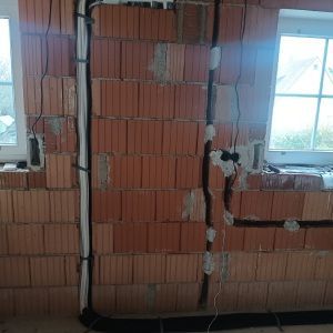 Eine Ziegelwand mit herausführenden Kabeln und einem Fenster. Lierheimer Kältetechnik