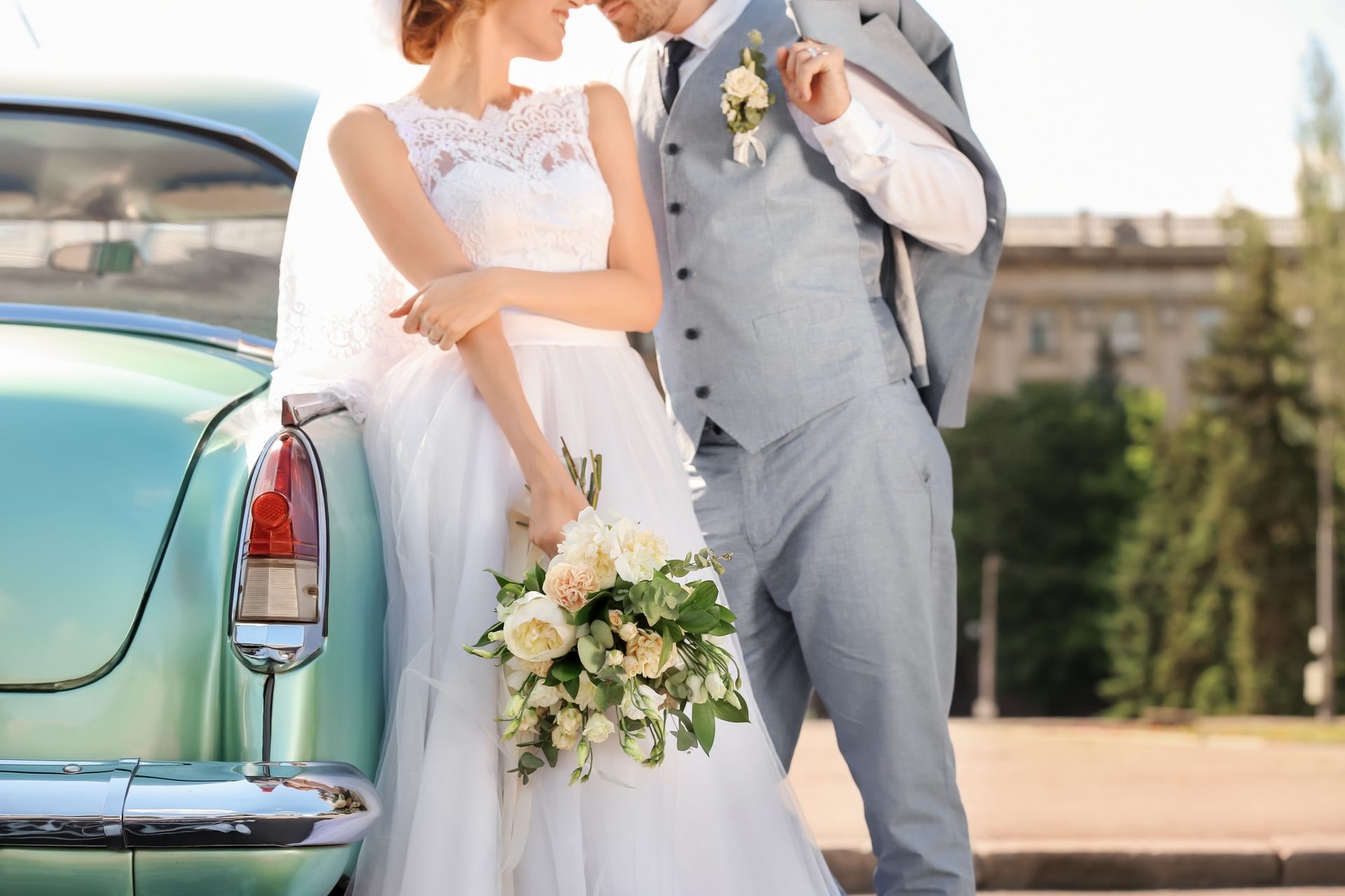Jeunes mariés devant une voiture