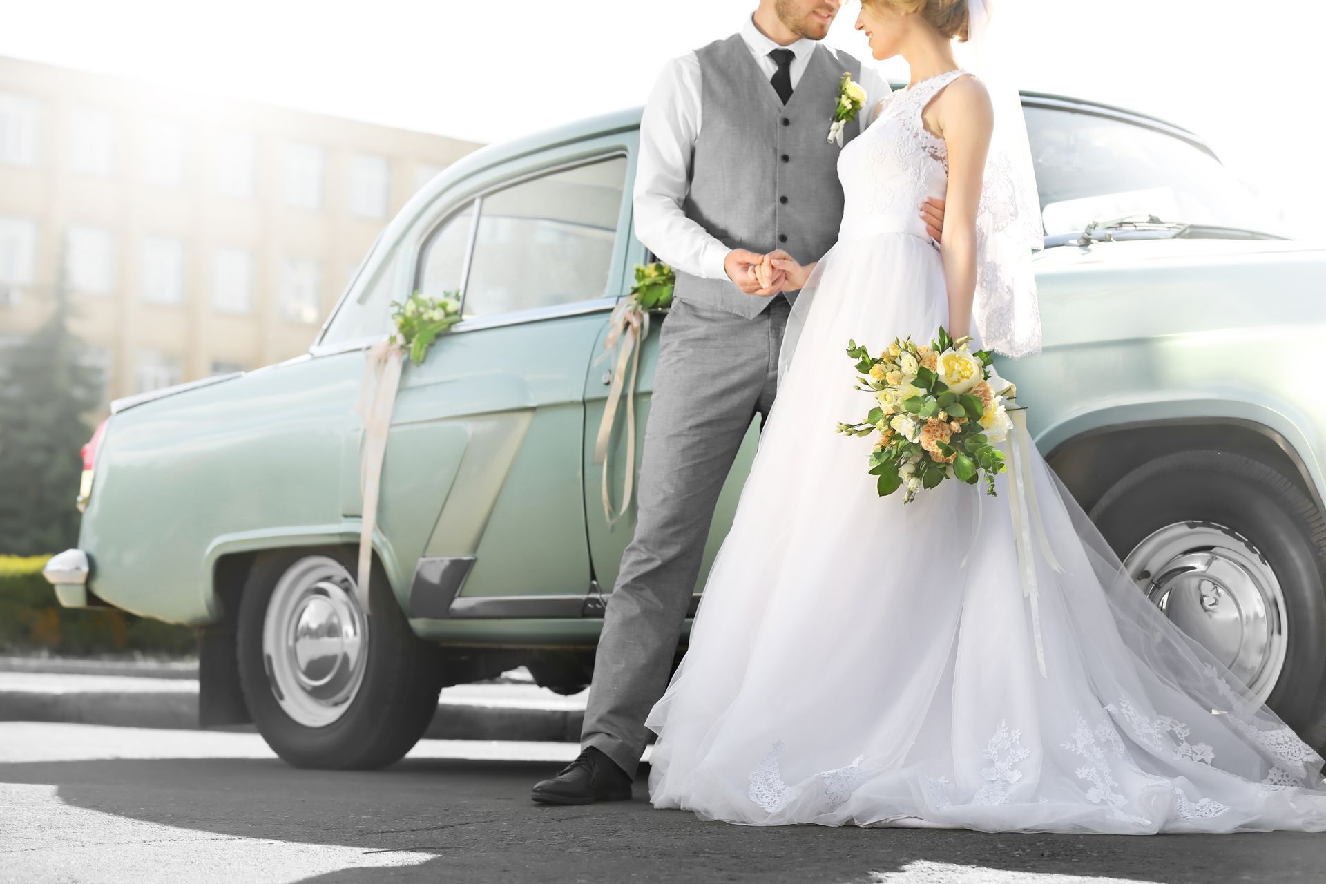Couple de jeunes mariés devant une voiture ancienne 