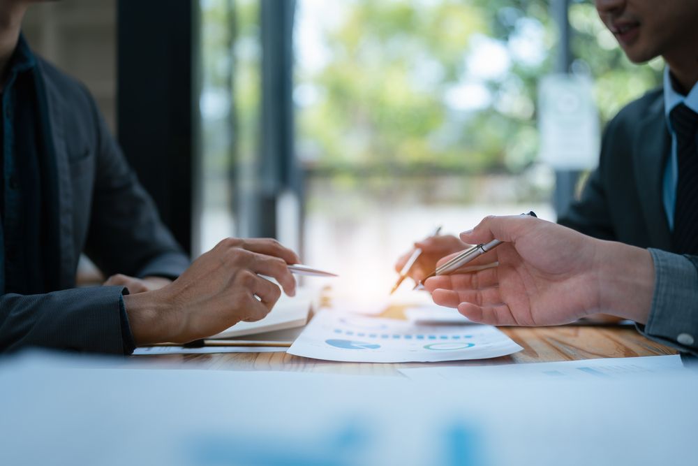 Dos hombres de negocios están sentados en una mesa teniendo una reunión.