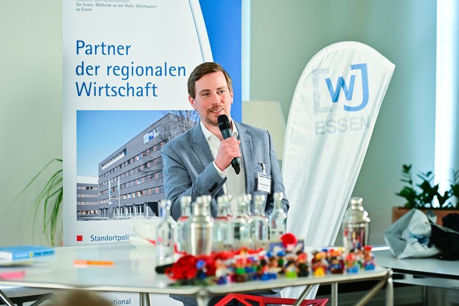 Ein Mann spricht an einem Rednerpult vor einem Banner eines regionalen Unternehmens und Konferenz-Erfrischungen.