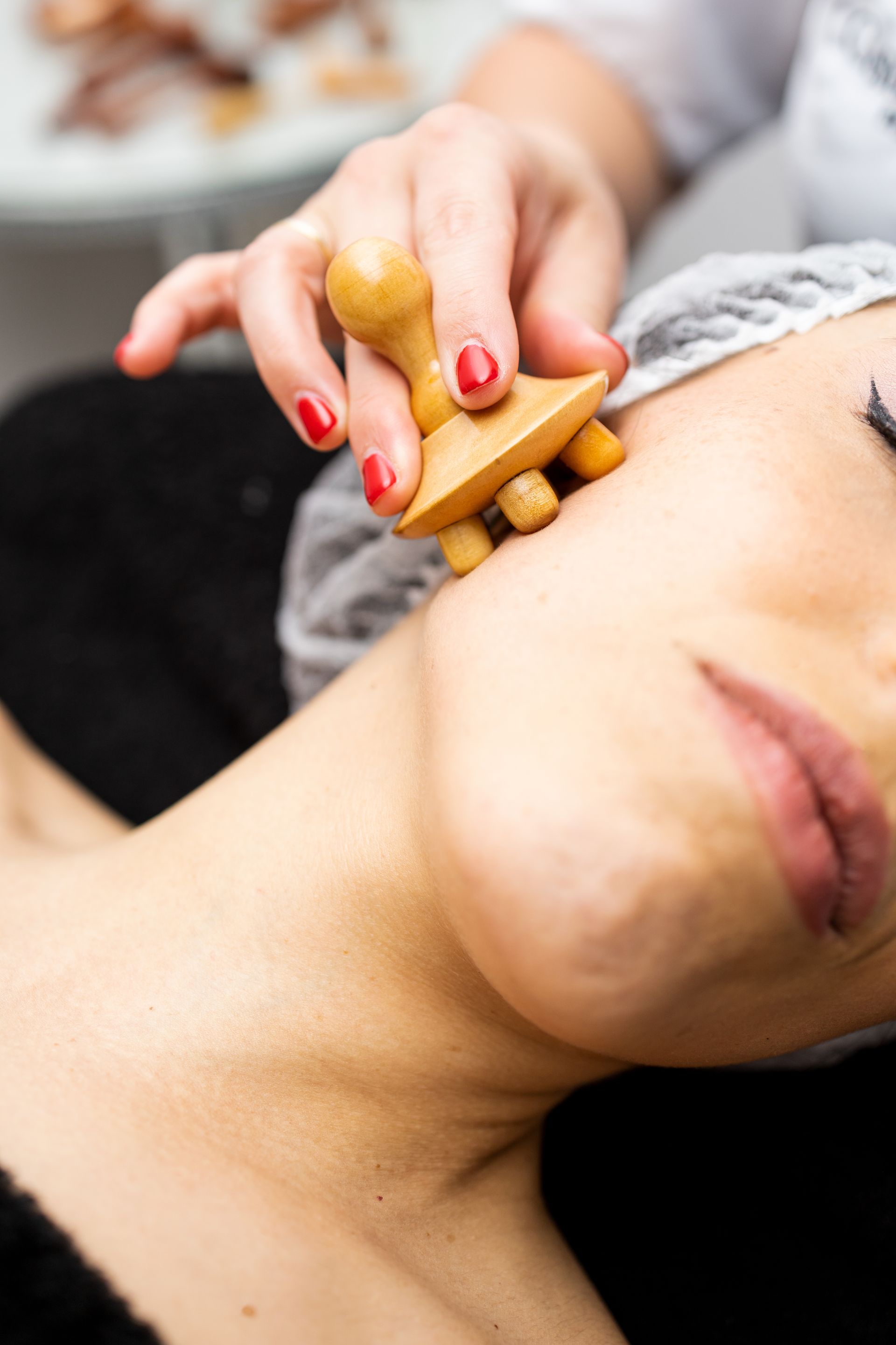 Une femme reçoit un massage du visage avec un outil en bois.
