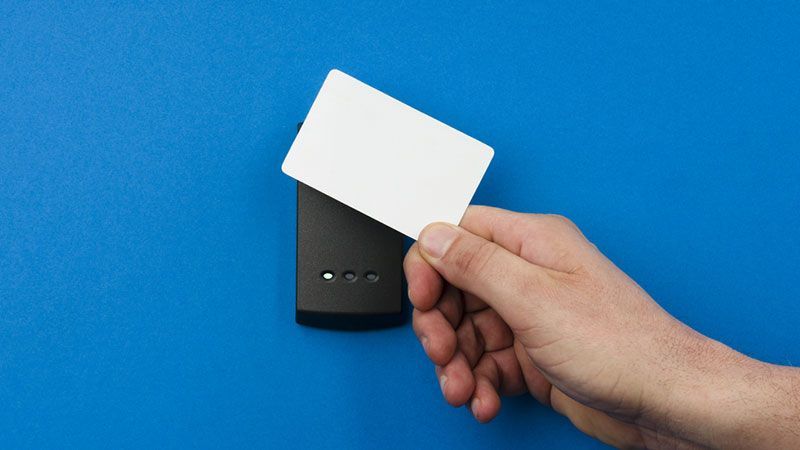 Main tenant une carte blanche au-dessus d'un appareil noir sur fond bleu