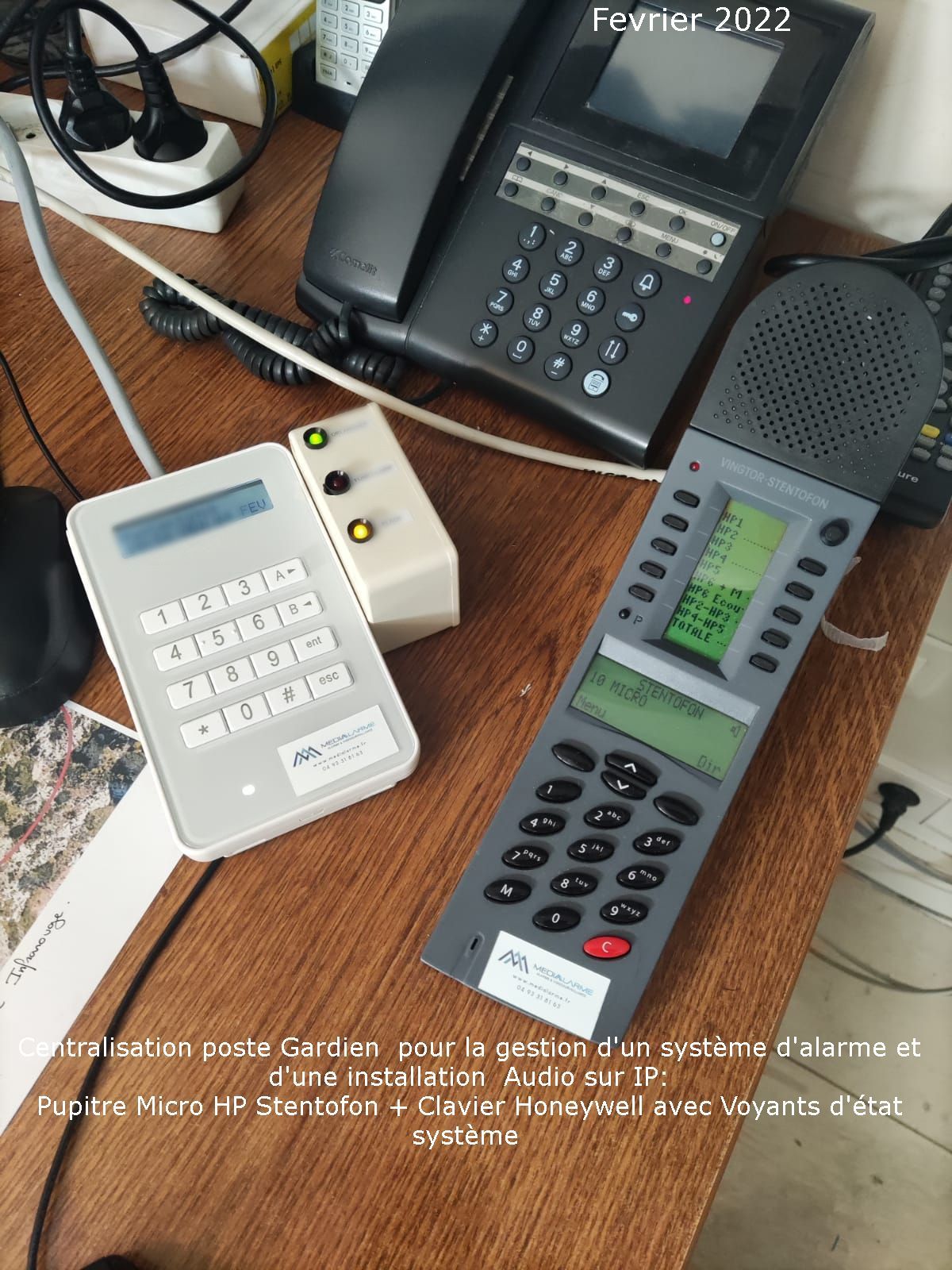 Plusieurs téléphones de bureau blancs et gris assortis et un téléphone haut-parleur noir posés sur une table en bois.