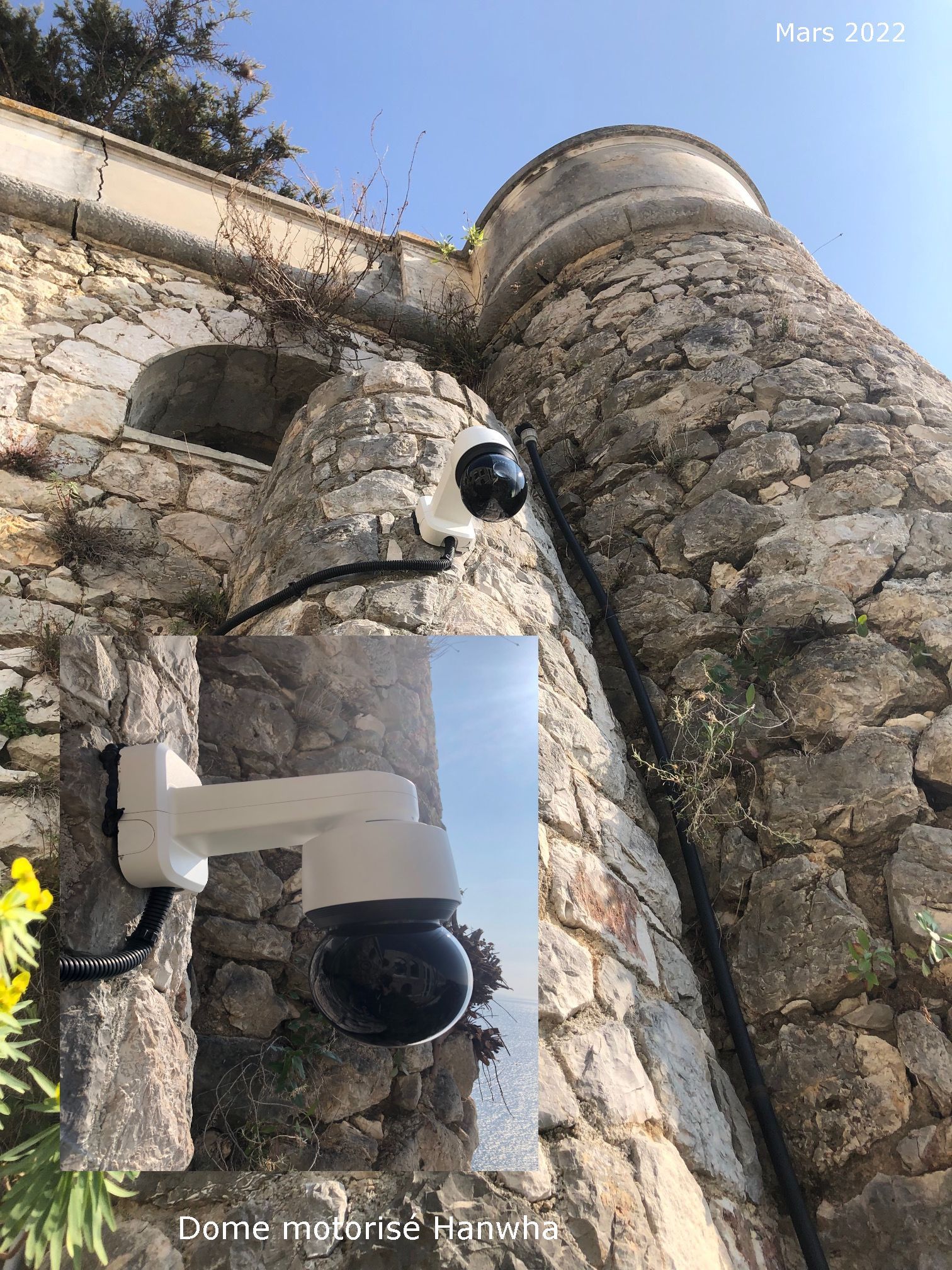 Caméra de sécurité fixée sur un mur de pierre à côté d'une arche et d'une tour sous un ciel bleu