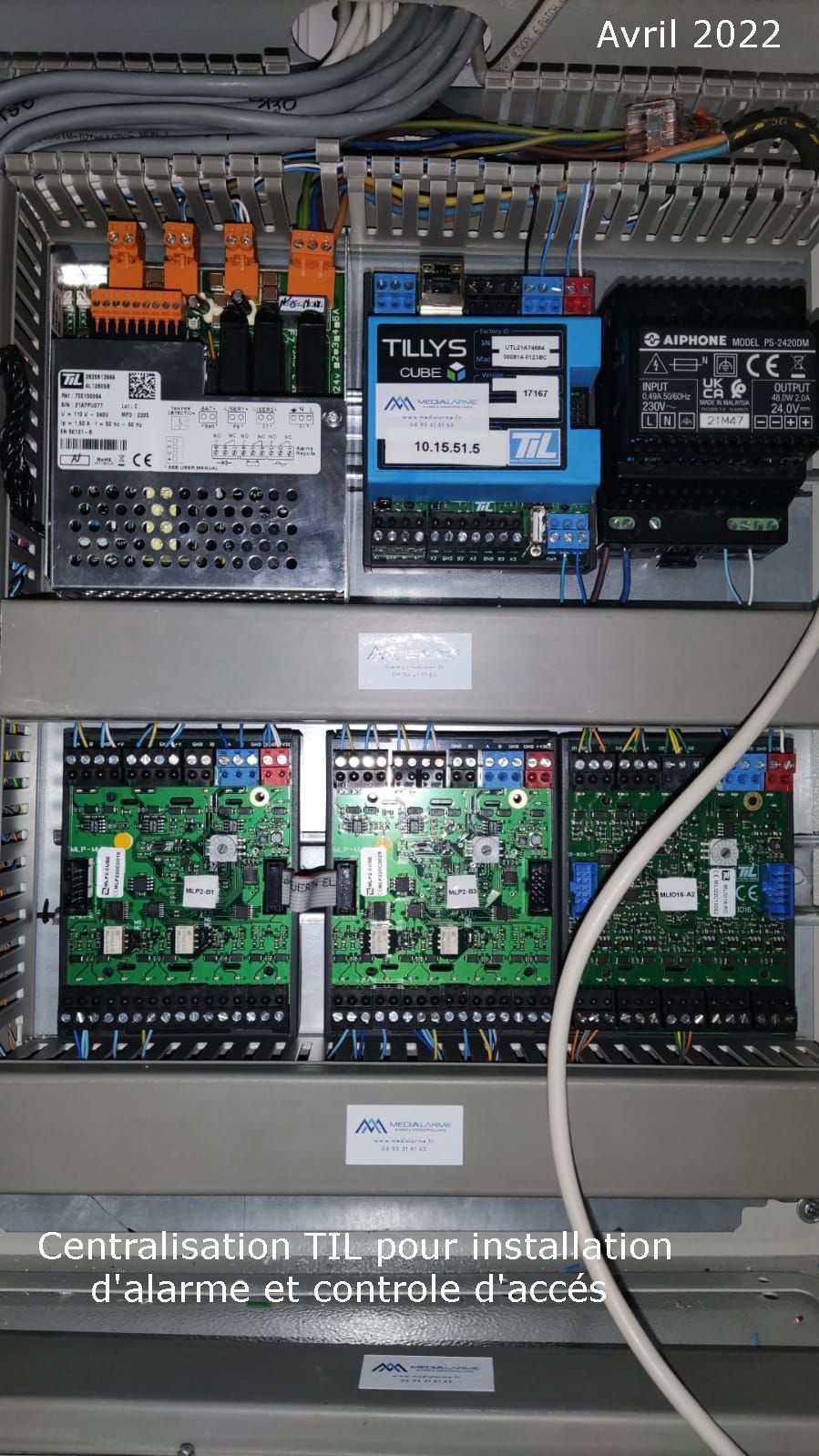 Armoire électrique ouverte avec cartes de circuits imprimés bleues et vertes, câblage et modules montés à l'intérieur.
