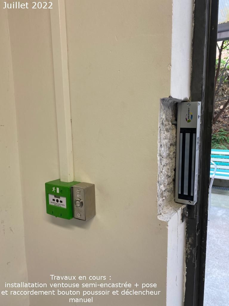 Mur avec une prise électrique verte et un loquet de porte métallique à côté d'une ouverture de fenêtre