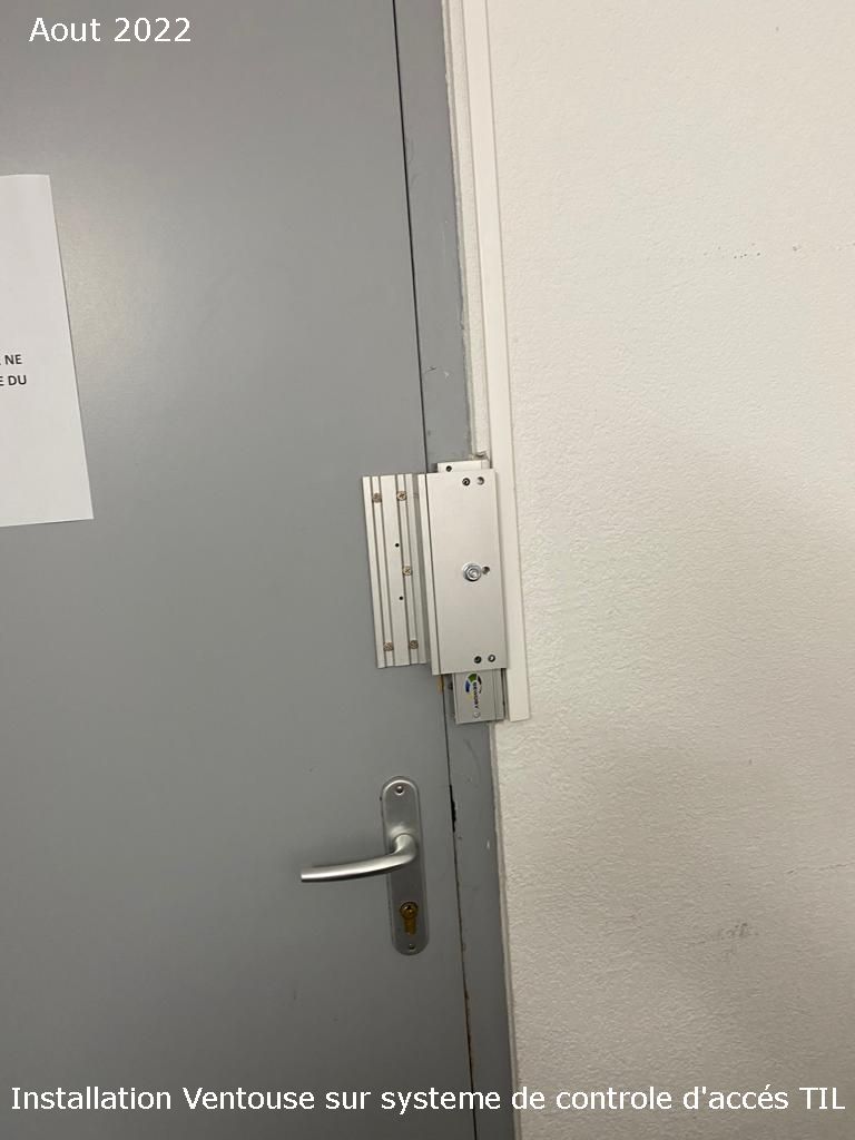 Porte grise avec poignée argentée et quincaillerie de contrôle d'accès montée sur le cadre.