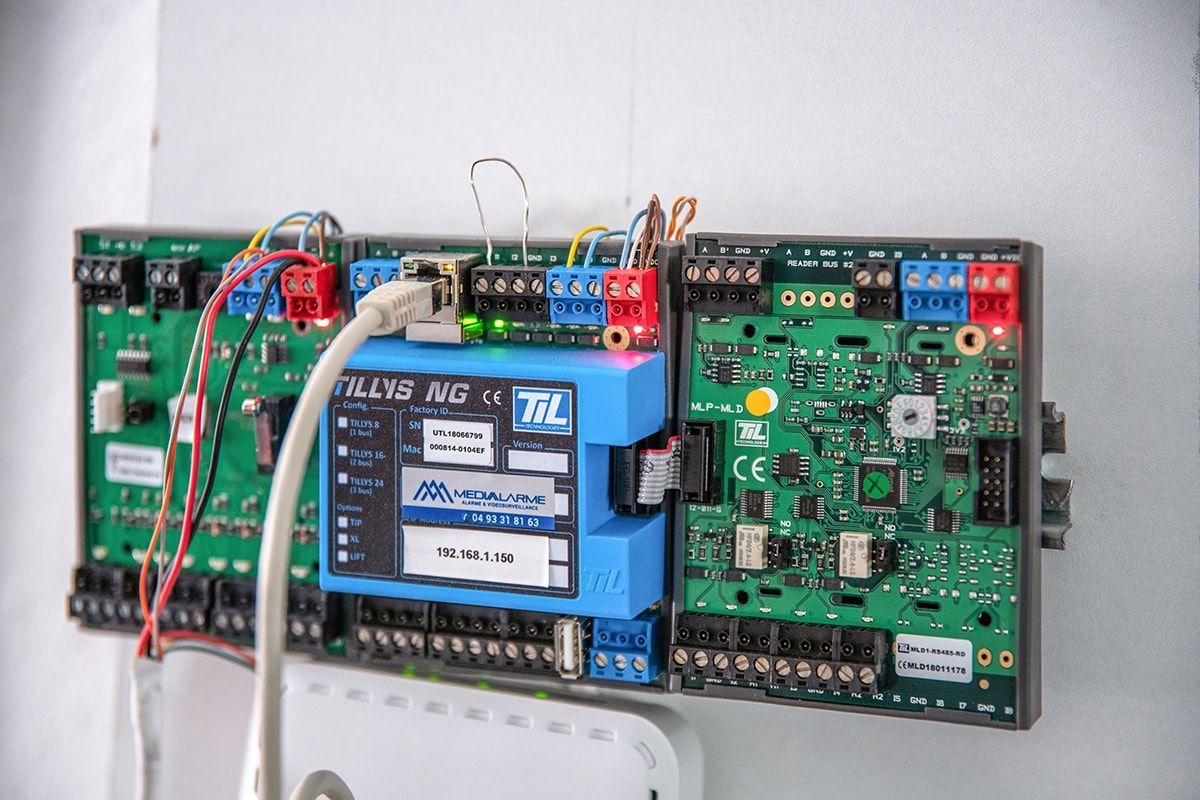Carte de circuit imprimé électronique avec un module bleu et des fils rouges montée sur un panneau mural