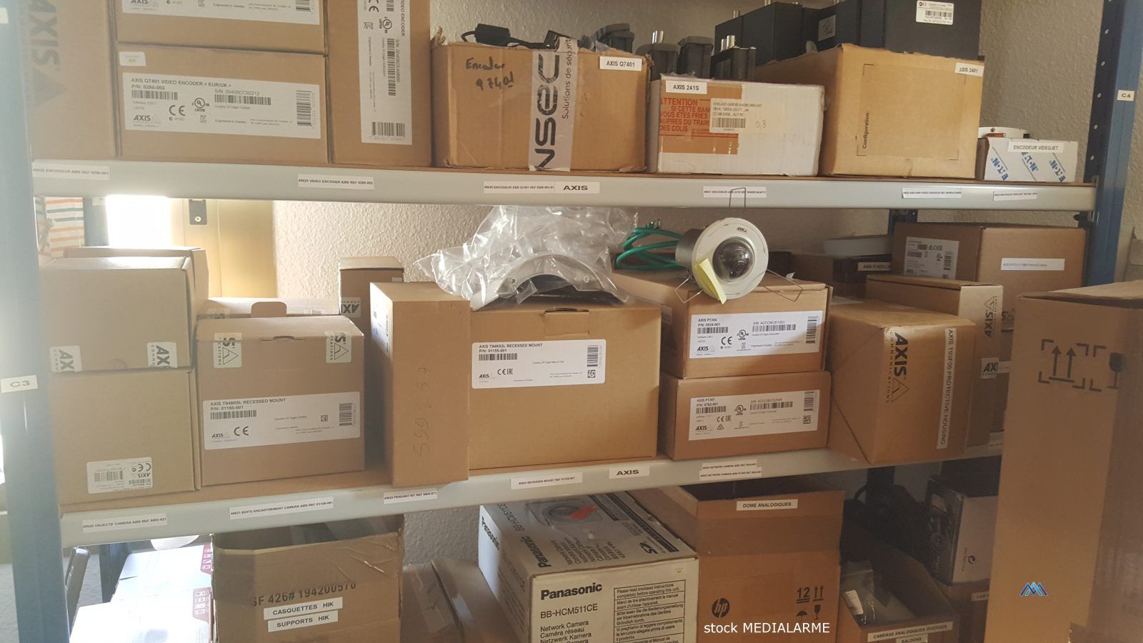 Des cartons empilés sur les étagères d'un entrepôt, avec leurs étiquettes et matériaux d'emballage dans une zone de stockage.
