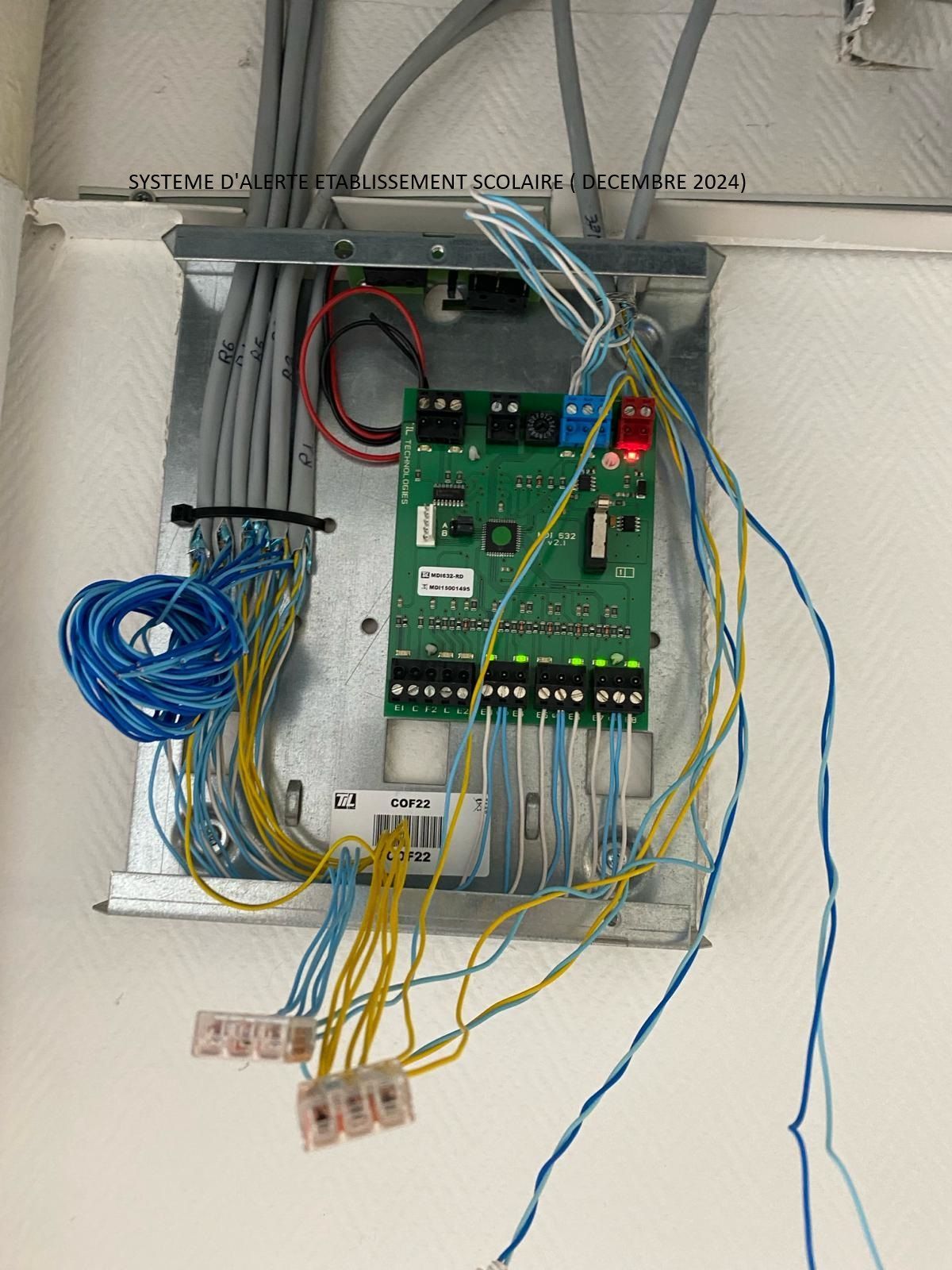 Tableau de câblage avec circuit imprimé vert, câbles multicolores et connecteurs montés à l'intérieur d'un boîtier métallique