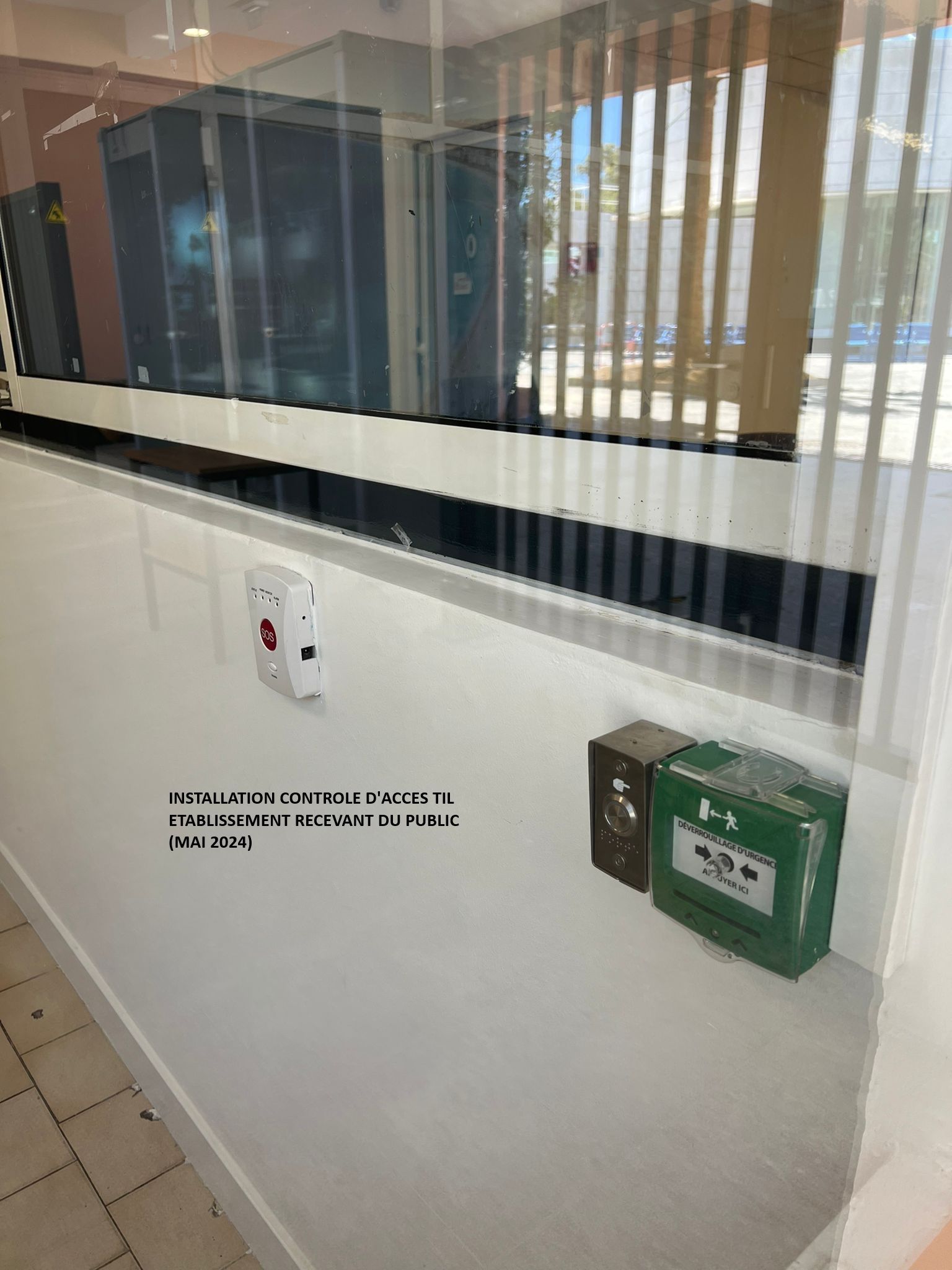 Couloir d'hôpital avec une borne d'appel d'urgence murale et un tableau électrique vert.