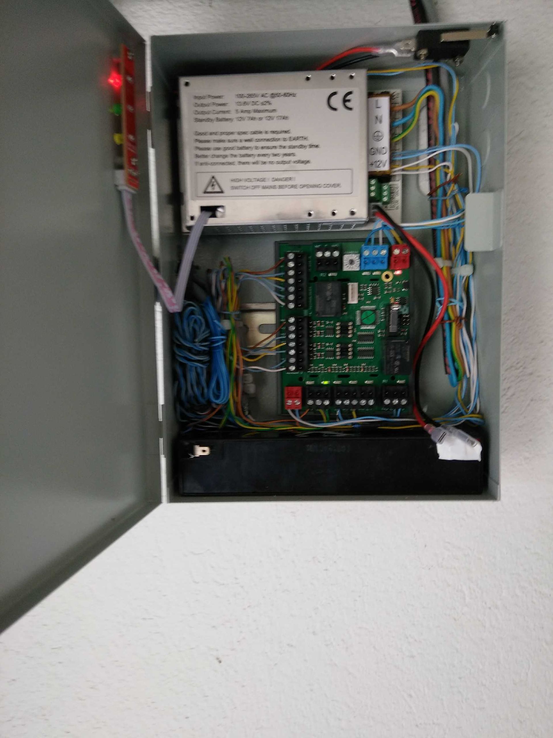 Panneau de commande électrique ouvert avec cartes de circuits imprimés, câblage et alimentation électrique dans un boîtier métallique.