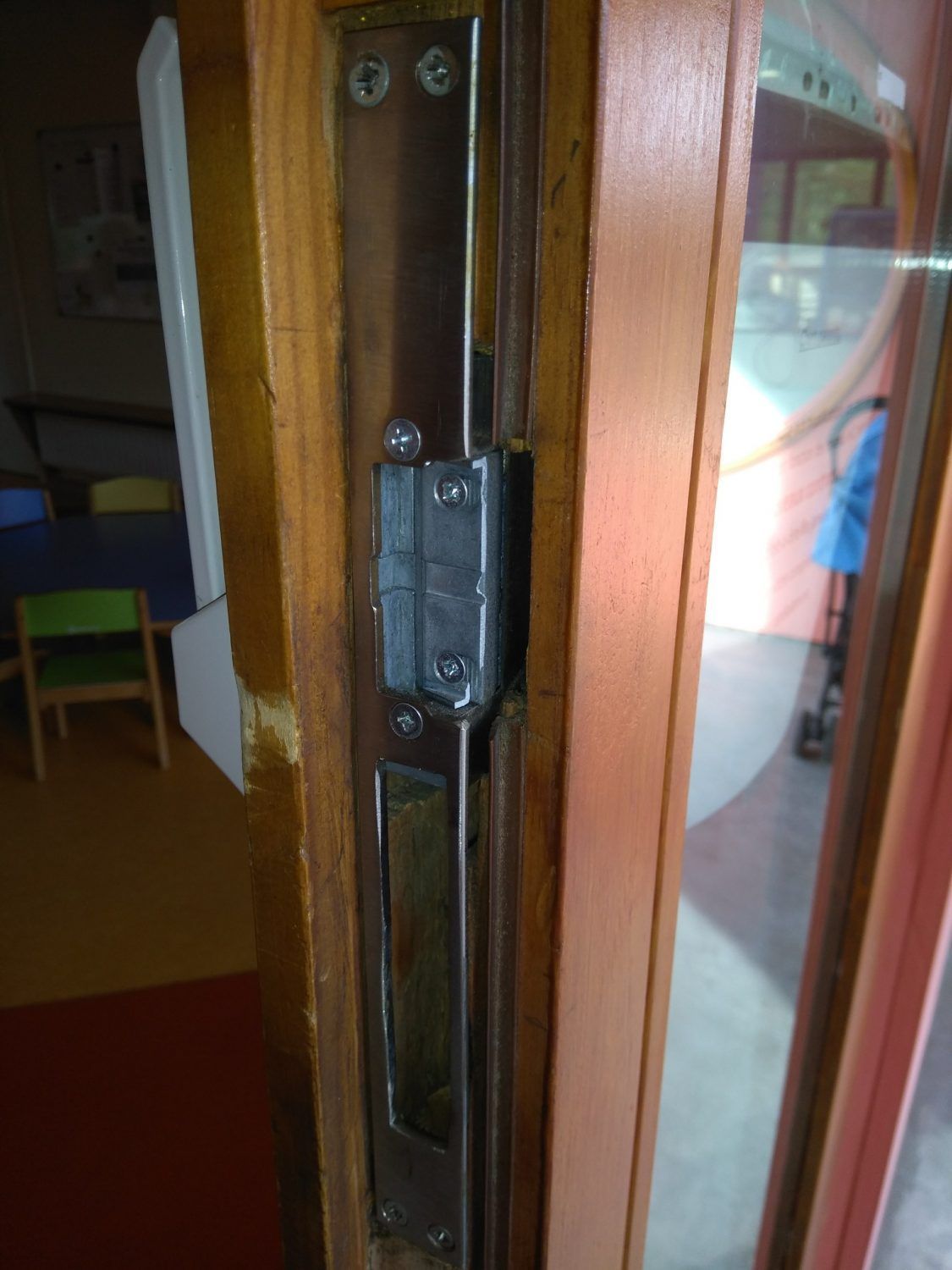 Gros plan sur un loquet et une poignée de porte en bois, avec des panneaux de verre à côté.