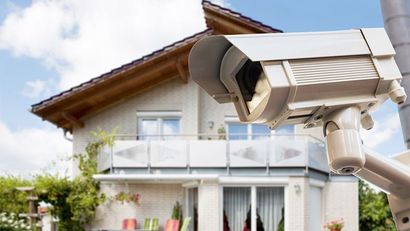 Caméra de sécurité installée sur une maison, donnant sur un balcon et un toit par une journée ensoleillée
