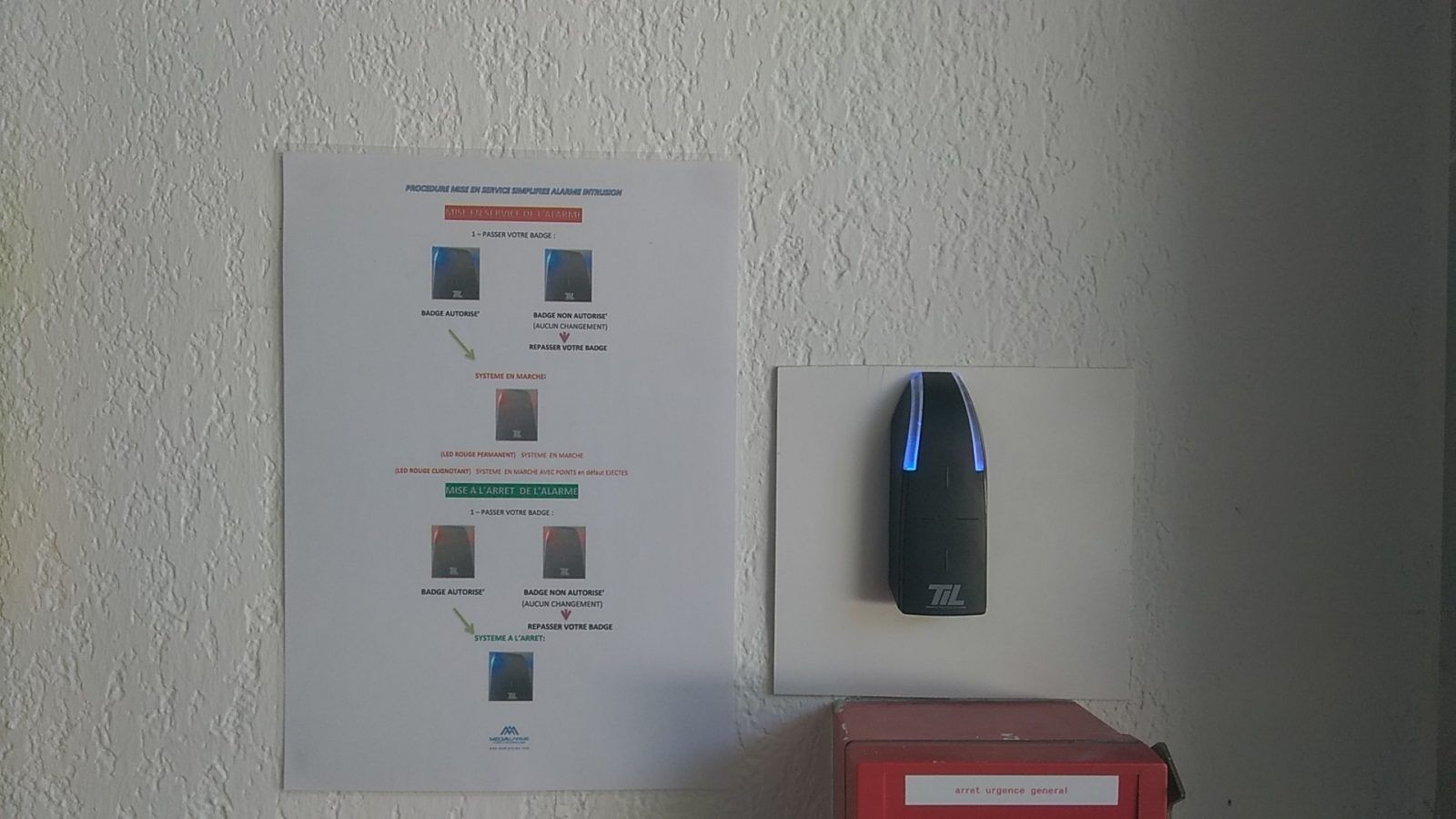 Appareil mural avec lumières bleues à côté d'une notice d'utilisation sur un mur texturé.