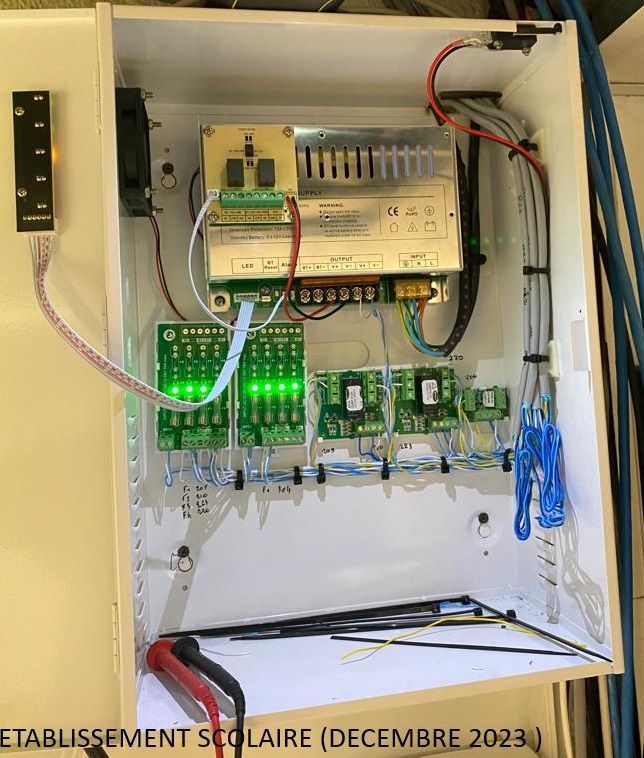 Armoire électrique ouverte avec cartes de circuits imprimés, câblage et LED vertes allumées à l'intérieur d'un boîtier blanc