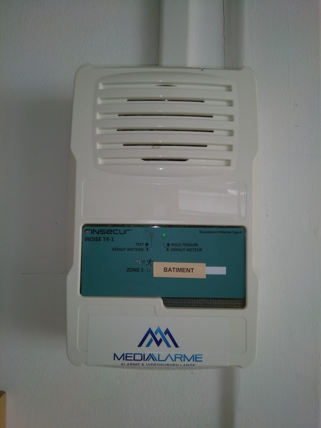 Interphone ou alarme murale blanche avec étiquette bleue et grille de haut-parleur ventilée