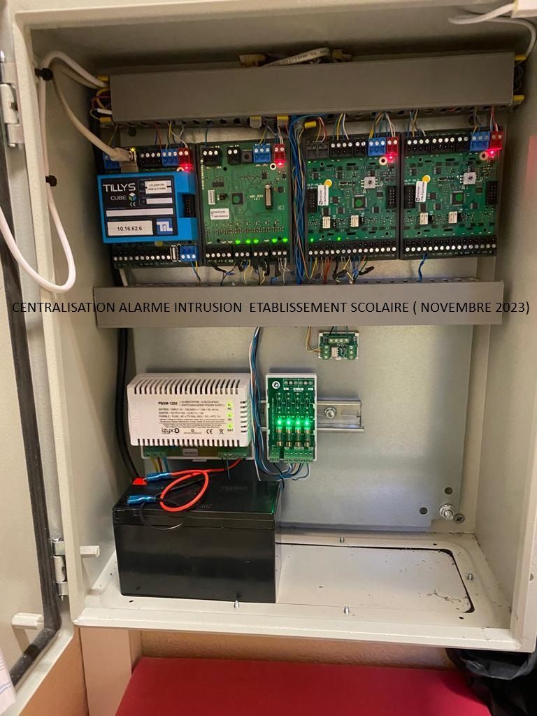 Panneau de commande électrique ouvert avec cartes de circuits imprimés, câblage et unité de batterie de secours noire.