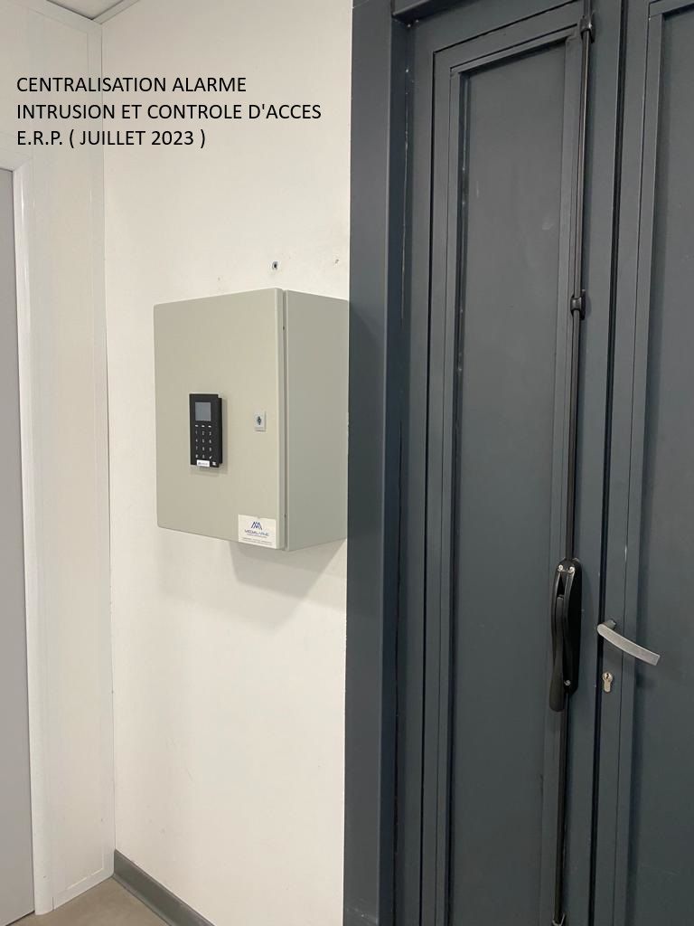 Mur du couloir avec un boîtier de commande beige à côté d'une porte métallique gris foncé