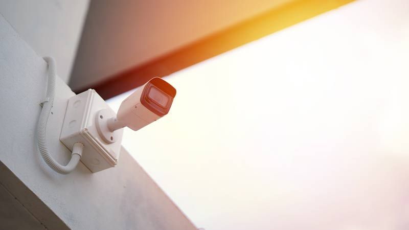 Caméra de sécurité murale émettant une lumière orange vive dans une pièce blanche