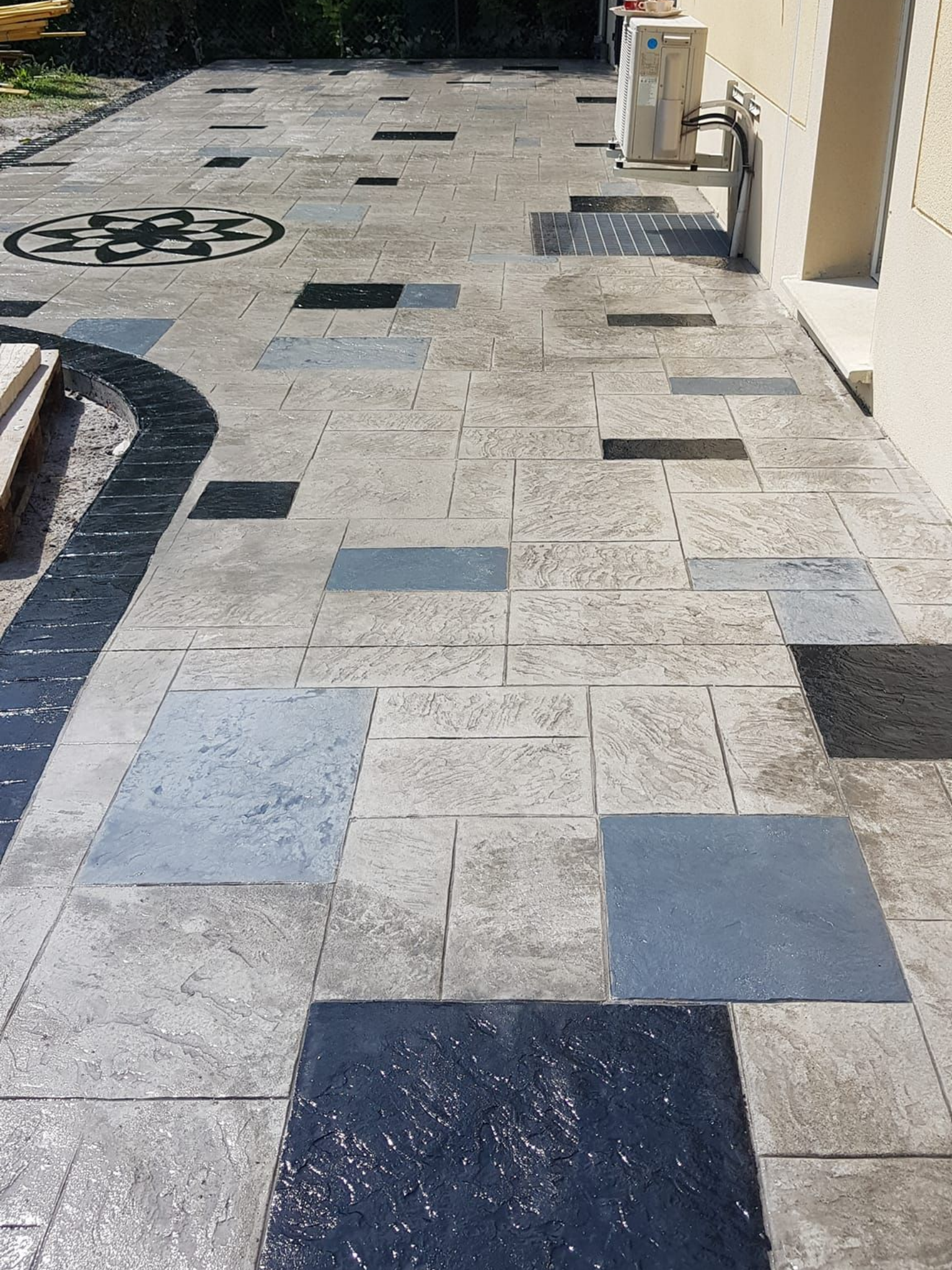 Une terrasse en béton imprimé, une rosace et des carreaux bleus, bleu marine et gris.