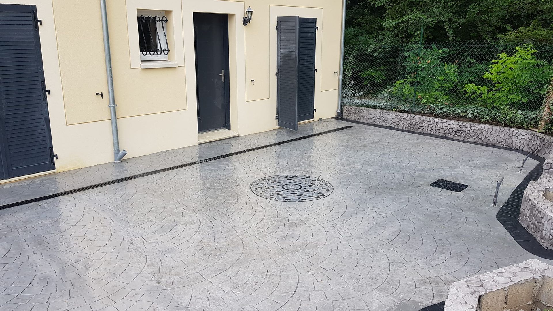 Terrasse en béton imprimé gris attenante à une maison beige.