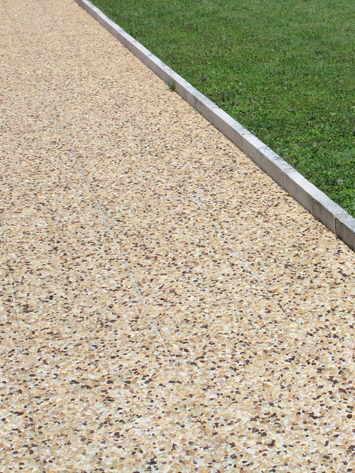 Un béton désactivé beige, une bordure et de l'herbe.