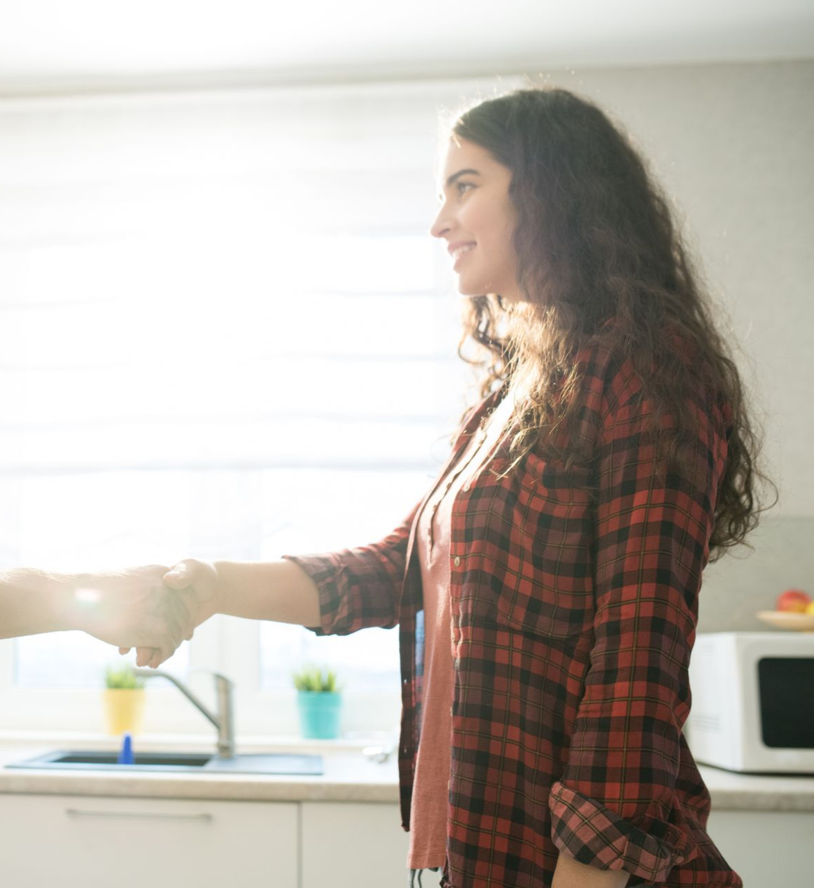Une femme en chemise à carreaux serrant une main.
