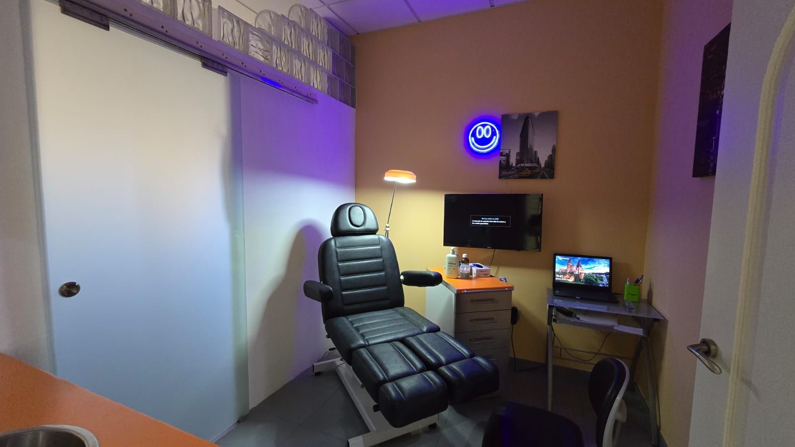 Interior de clínica dental con sillón. Paredes brillantes con detalles en azul y naranja.