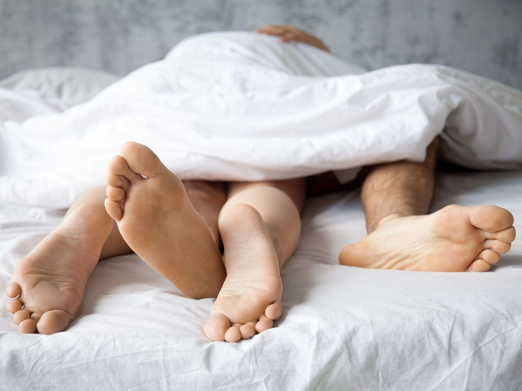 Pieds d'un couple sous la couette