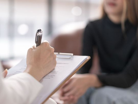 Personne écrivant sur une feuille avec une femme devant