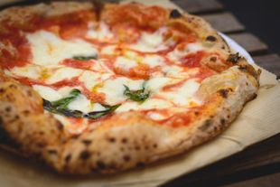 Eine Pizza mit Schinken und Käse auf weissem Hintergrund.