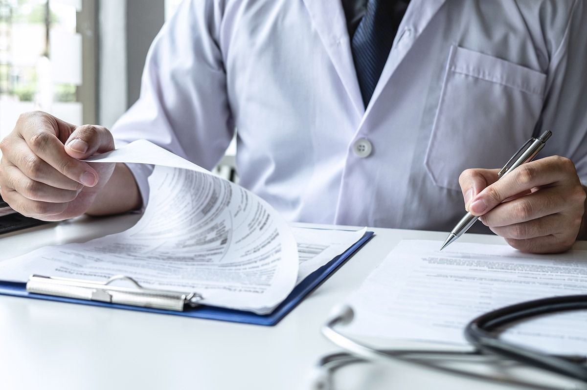 Un médico revisa documentos en un escritorio con un estetoscopio cerca.