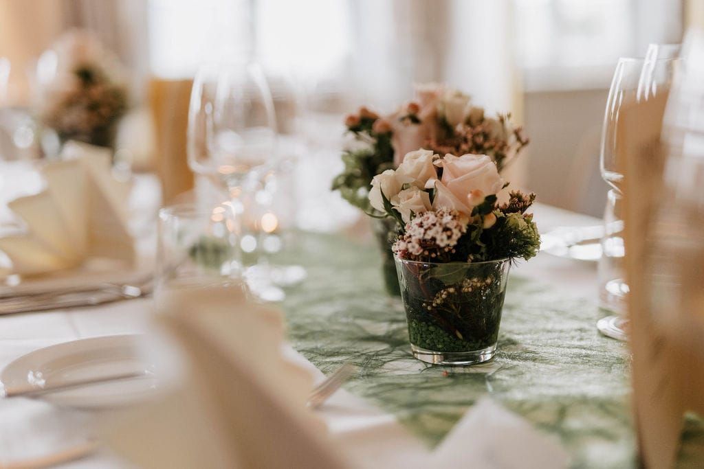 zwei Blumenarrangements mit weißen Lilien und Rosen auf einem Tisch